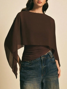 Detail van koffiebruine chiffon cape-top gelaagd met een klassieke blauwe jeans