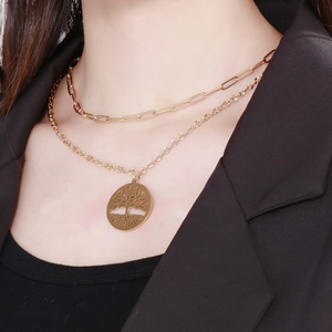 Close-up of a double-layered gold tree of life necklace on a black suit model