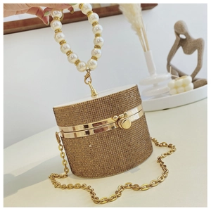 Detail of champagne gold evening bag with rhinestones, pearl handle, and metal chain