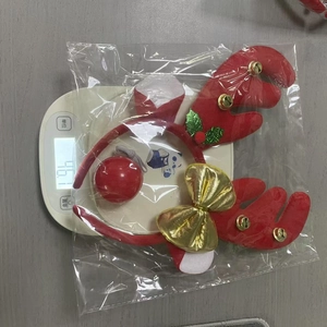 Close-up of red reindeer antler headband with bells on a scale showing 46g weight