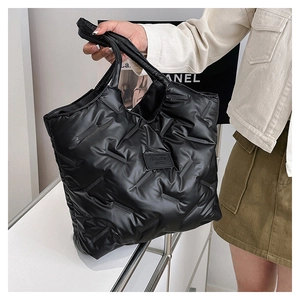 Detailansicht der schwarzen gesteppten Puffer-Tasche mit modischem Stoffetikett