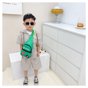 Green school bus chest bag shown on child model in a warm indoor setting