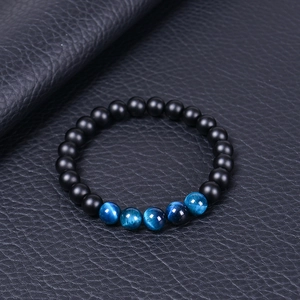 Vue détaillée des perles noires mates et de l'œil de tigre bleu sur fond de cuir