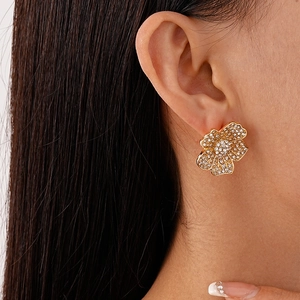 Close-up detail of luxurious gold flower earrings with pavé crystals on a female model