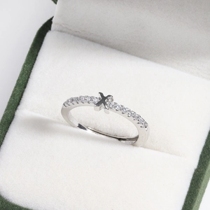 Detailed macro of a silver diamond X-shape ring inside a green velvet jewelry box