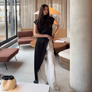 Elegant black mock neck sleeveless satin top with asymmetrical hem and white trousers