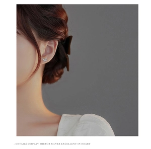 Detail view of a model wearing a silver butterfly stud earring with white zircon stones