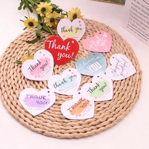 Flat lay of heart-shaped thank you gift tags on a woven mat for small business packaging