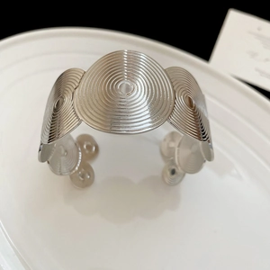 Macro detail of silver geometric bangle featuring unique spiral texture and wide C-shape design