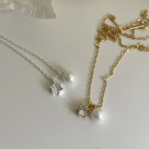 Detail of silver and gold necklaces featuring 6-prong zircon and white round pearls
