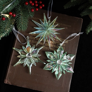 Iridescent acrylic snowflake Christmas ornaments on vintage book for festive tree decor