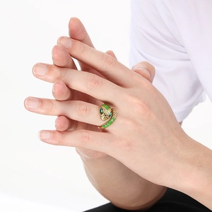 Macro detail of golden snake ring featuring green enamel scales and emerald-like eyes