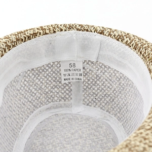 Detail view of woven straw hat showing the 100% paper material label and sweatband