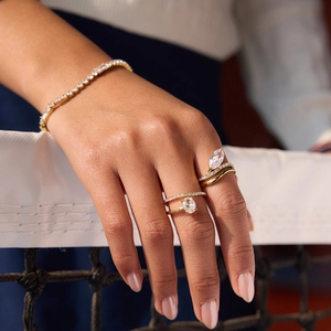 Dettaglio del bracciale tennis in zircone e anelli dorati a doppio strato su modella