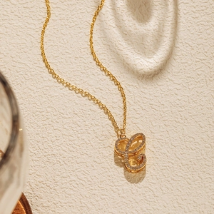 Close-up of a gold-plated necklace featuring a crystal-encrusted letter C pendant detail