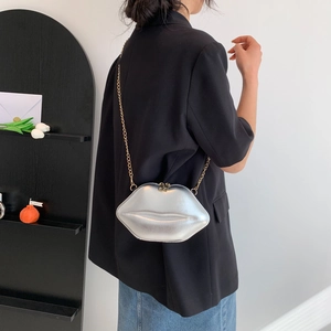 Silver lip-shaped crossbody bag with gold chain strap shown on a shoulder