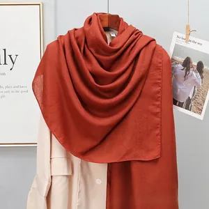 Detailed close-up of a caramel linen cotton scarf texture on a wooden hanger