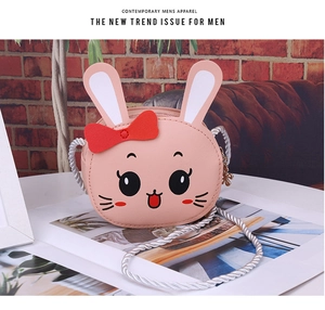 Detailed view of pink rabbit shoulder bag with 3D ears and braided strap on brick background