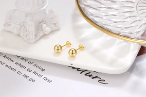Detailed macro view of polished gold round stud earrings with matching butterfly backs