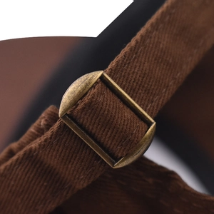 Nahaufnahme der braunen Canvas-Lasche mit Bronze-Schnalle an der bestickten Kappe