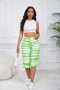 Summer casual outfit featuring green tie-dye shorts and a white crop top in a bright room