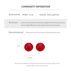 Detail view of round red resin earrings with gold leaf foil showing size and weight