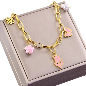 Gold charm bracelet with pink tulip, butterfly, and bee pendants on jewelry box