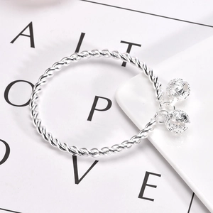 Ancient style silver twisted bangle with two hollow bell charms in a polished metal finish