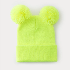 Dettaglio del cappello in maglia giallo neon con due grandi pompon su sfondo grigio chiaro