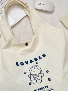 Cream canvas tote bag with cute blue rabbit print and laptop on desk for campus life