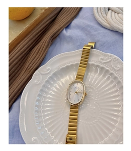 Detail of vintage gold quartz watch with oval dial displayed on a ceramic plate