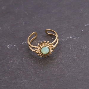 Gros plan détaillé d'une bague tournesol dorée avec zircon vert et anneau texturé