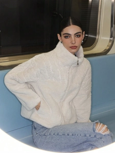 Detail of white plush jacket with high collar, metal zipper, and embossed faux fur texture
