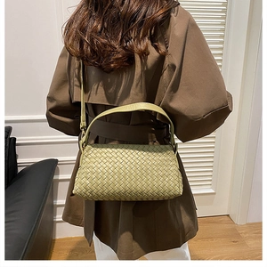 Détail de la texture tressée d'un sac à bandoulière vert clair porté par un modèle
