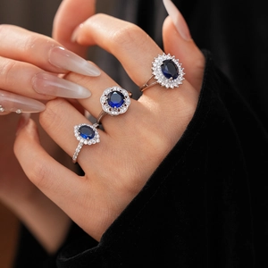 Detail of silver rings with blue zircon flower and diamond pavé on model's hand
