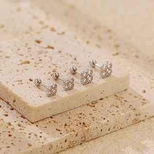 Macro view of silver four-leaf clover stud earrings with zircon and screw ball backs