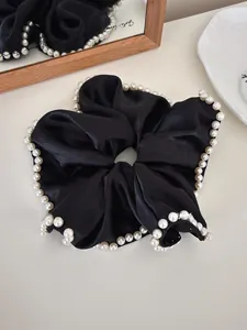 Close-up of black satin oversized scrunchie with elegant pearl edge detailing