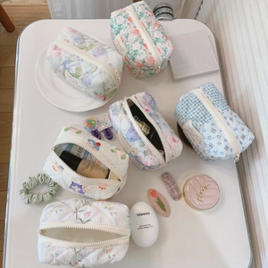 Quilted floral and plaid cotton makeup bags arranged on a tray with cosmetics