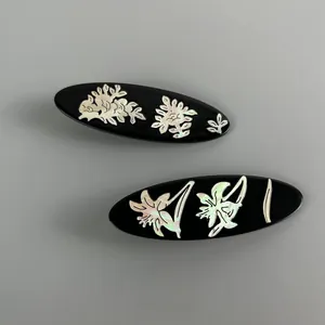 Detail of oval black hair clips with delicate shell-inlaid floral patterns and iridescence