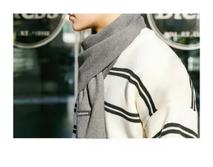 Close-up of grey cashmere scarf with soft tassel texture on a knit sweater