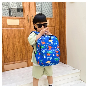 Close-up of bright blue preschool backpack featuring colorful cartoon dinosaur prints