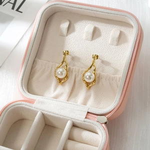 Nahaufnahme von eleganten 18k Gold-Ohrringen mit Perlen in einer rosa Schmuckschatulle