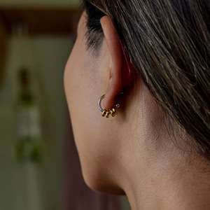 Close-up of minimalist two-tone C-shape hoop earring on ear with gold rings