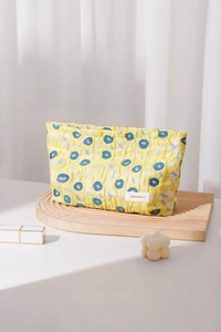 Close-up of yellow floral cosmetic bag with textured fabric and elegant logo tag