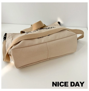 Detail view of the beige canvas tote bag bottom structure and Summer lettering print