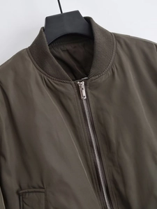 Detail of olive green bomber jacket neckline with rib-knit collar and metal zipper