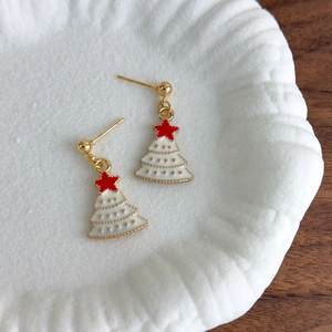 Golden Christmas tree stud earrings with white enamel and red star detail on white plate