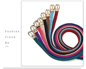 Detail of woven skinny belts in various colors featuring golden metal pin buckles