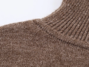 Gros plan sur le pull en maille marron montrant la texture douce et le col à côtes
