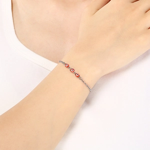 Detail view of silver evil eye bracelet with red beads worn on a female wrist